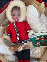 Full view of the 7-inch Madame Alexander Eskimo doll in red coat, fur trimmed, in box with white paper wrapping.