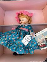 Madame Alexander Miss Muffet doll wearing blue dress with pink floral prints and pink bonnet inside original pink box, showing doll and box condition