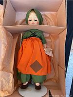Full view of Madame Alexandra Poor Cinderella doll lying in original box on tissue paper, showing the full costume and overall condition.