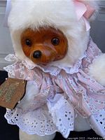 Close-up of Raikes Bear face showing wooden carved features and pink striped dress with lace