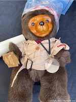 Front view of Raikes Bear Cecil showing carved wooden face and beige jacket with 'Raikes Bears' tag
