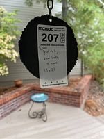 Photo of the MaxSold lot tag hanging from the wrought iron stand and blue birdbath visible in the background.