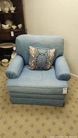 Front view of denim armchair with decorative throw pillow