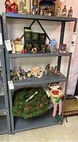 Metal shelving unit with three shelves displaying various decorative and collectible items (not included).