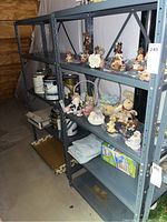 Two gray-blue metal storage shelves with multiple shelves in a basement setting. Shelves are empty with no contents. Close-up of bolts on vertical supports showing construction details.