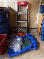 View of the Husky ladder, extension cord, and tarps stacked near the garage wall