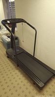 Full side view of the treadmill showing running belt, handrails, and console area.