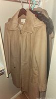 Beige wool-blend women's coat with collar and front pockets hung on a hanger.