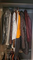 Seven women's outerwear jackets and coats hanging on rack including a grey Pendleton wool suit jacket with visible tag.