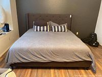 Front view of assembled upholstered bed frame with grey bedding