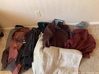 Several winter coats and jackets laid out on carpet, showing variety of colors and styles.