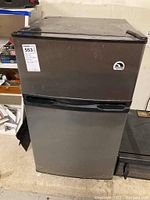 Front view of the stainless steel Igloo mini fridge with freezer on top, showing sticker and logo.