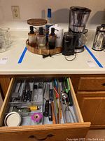 Full countertop view showing coffee maker, grinder, coffee caddy with jars and pod holder, and open drawer with kitchen utensils