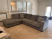 Full view of grey sectional sofa with chaise and cushions in living area