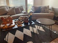 Both tables positioned on patterned area rug in living room, wood and metal materials visible, couch background