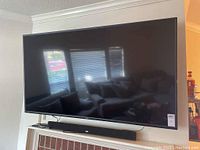 Front view of Vizio 70" TV mounted on wall with RCA sound bar beneath