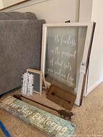 Decorated window frame with text and various wooden and metal arrows, and a rolled canvas print on carpet near couch.