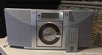 Full front view of Sanyo boombox with fabric speakers and CD player door, remote control placed next to it.
