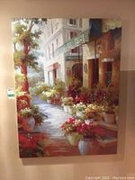 Full view of the 48x36 inch canvas print showing the street scene with building, potted plants, and flowers.