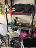 Sports and miscellaneous items arranged on garage shelves including hammock and fishing net.