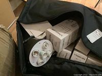 Full view inside the carrying case showing multiple light bulb boxes and a circular multi-socket light fixture panel