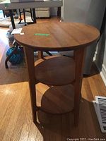 Photo showing the front view of the round wooden end table, highlighting the tabletop and two lower shelves.
