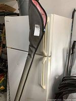 Rod stored inside gray zip-up case hung on refrigerator