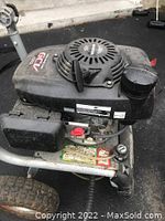 Side view of black Honda GCV engine housing mounted on silver metal frame with wheels