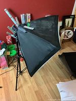 Full view of the black softbox light diffuser attached to an adjustable tripod stand, showing overall size and structure.