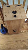 Full view of the pine wood potato bin standing on a hardwood floor next to a blue kettlebell.
