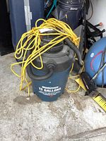 Front and top view showing full shop vacuum, portable blower, and yellow extension cord coiled on top.