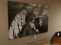 Front view of the three canvas panels hung as a triptych showing black and white angel statue image.