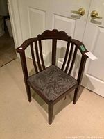 Photo of vintage wooden chair showing angled front view, fabric seat with floral pattern and curved backrest with three vertical slats.