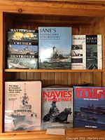 Shelf displaying seven naval books with visible titles related to battleships, cruisers, destroyers, Jane's Fighting Ships, World War II at Sea and Canadian Naval Forces.