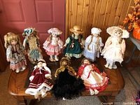 Full group of nine porcelain dolls on a wooden table, varied costumes and hairstyles