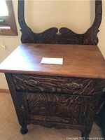 Front view of antique wooden wash stand showing drawer and cupboard door with brass handles and carved wood grain.