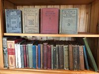Books arranged on two wood shelves with titles visible, covering history and grammar topics including 'The Story of the British People' and 'The Story of Greece and Rome'.