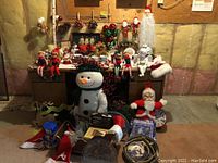 Wide shot showing lot contents including large snowman, Santa figure, elf dolls, glittery pinecones, reindeer figures, and Santa hats.