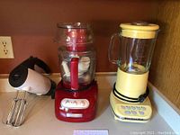 Photo of all three appliances showing KitchenAid food processor, blender, and Sunbeam hand mixer.