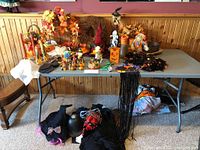 Table with multiple Halloween and fall-themed decor items including wreaths, figurines, candles, garlands, and small decorative objects.