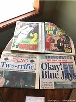 Four historical World Series newspapers arranged on floor, featuring Toronto Blue Jays headlines and related sports news.