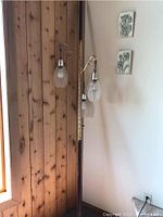 Full view of vintage tension pole lamp showing wooden background wall and wall art.