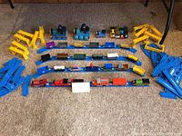 Full lot overview showing trains, rail cars, trucks, and track components arranged on carpeted floor