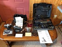 Full view of the lot showing two 35mm cameras, two video camcorders, cases, manuals, and straps on a wooden table.