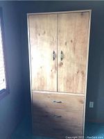 Full view of vintage wooden wardrobe showing natural wood finish, two doors on top, and two drawers below.