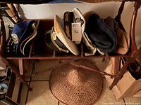 Overview of the hats arranged on a wooden rack showcasing the captain's hats, baseball hats, and bucket hat with woven straw hat underneath.