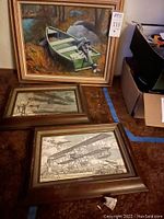 Three framed wall art pieces displayed on carpet: one acrylic boat painting and two aviation-themed prints below.