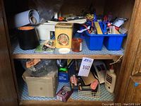 Shelf with boxes and containers holding twine, tape rolls, glue, hardware, and tools