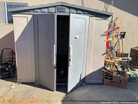 Exterior front view of plastic shed, doors partially open, showing overall condition and double-door entry.