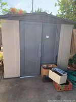 Exterior front view of large grey/tan plastic shed with double sliding doors